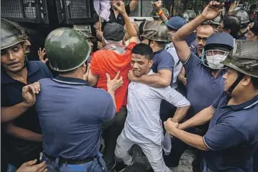  ?? Sankhadeep Banerjee NurPhoto ?? A PROTESTER struggles with police during an anti-government demonstrat­ion in Kolkata, India. The Aug. 5 protest over rising food prices and unemployme­nt was held by the main opposition Congress party.