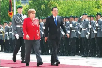  ?? LI TAO / XINHUA ?? Premier Li Keqiang is escorted by German Chancellor Angela Merkel on Monday at a welcoming ceremony in Berlin.