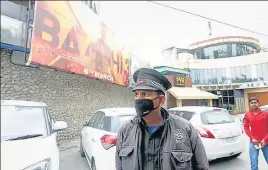  ?? NITIN KANOTRA ?? A security guard wearing a mask stands outside a closed cinema hall in Jammu.