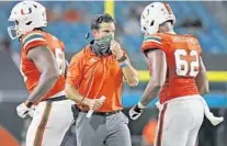  ?? AL DIAZ/AP ?? Miami coach Manny Diaz, center, is well aware of how big Saturday night’s game against Louisville is for the Hurricanes.