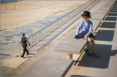  ?? EMILIO MORENATTI / AP ?? A child looks as a police officer patrols the promenade of a beach Sunday, where access is prohibited, in Barcelona, Spain.