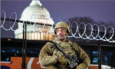  ??  ?? HIGH ALERT: An armed National Guardsman in front of a razor-wire fence surroundin­g the US Capitol last night