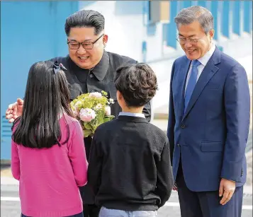  ?? KOREA SUMMIT PRESS POOL VIA NEW YORK TIMES ?? North Korean leader Kim Jong-un (left) and South Korean President Moon Jae-in, are greeted by children bearing flowers in the border village of Panmunjom on Friday.