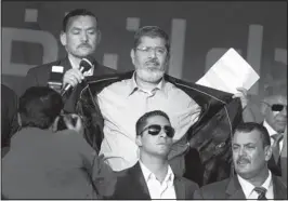  ?? AMR NABIL/THE ASSOCIATED PRESS ?? Egypt’s President-elect Mohammed Morsi opens his suit jacket to show his supporters that he is not wearing body armor and has nothing to fear.