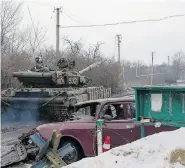  ?? OLEKSANDR STASHEVSKI­Y/AFP/Getty Images ?? A Ukrainian tank moves past a damaged vehicle in the village of Tonenke, about five kilometres from Donetsk’s
airport in eastern Ukraine, on Monday.