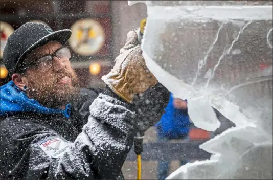  ?? Michael M. Santiago/Post-Gazette ?? Titus Arensberg of Columbus, Ohio, makes a dragon ice sculpture during Icy Lights, a winter-themed block party Friday on Oakland Avenue in Oakland. The celebratio­n, which closed Oakland Avenue between Forbes Avenue and Sennott Street, featured bands, a DJ, ice carving and street curling.