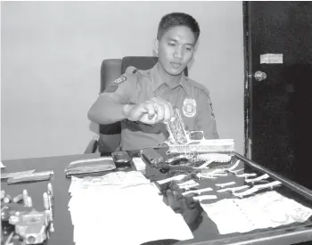  ?? (ALAN TANGCAWAN) ?? MGA EBIDENSIYA. Si PO1 Emmanuel Deriada sa Pusok police station sa dakbayan sa LapuLapu nipakita sa mga ebidensiya nga druga, kuwarta ug mga armas gikan sa duha ka mga suspek sa illegal drug operation againts batok ni Noel Quintero. Quintero ug laing uban nga namatay sa shoot out tali sa kapulisan kagahapon sa kaadlawon.