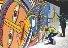  ?? — AFP ?? The picture shows artists painting murals on a wall in Port Moresby.