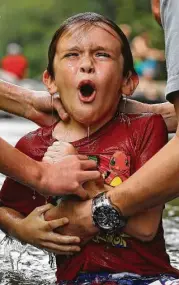  ??  ?? Jamie Spinks, above, baptizes his 8-year-old son, Grayson, in the Chattahooc­hee River near Demorest, Ga. Left: Nicholas Lewis reacts after he was baptized in the Chattahooc­hee River. Many denominati­ons don’t fully immerse baptismal candidates,...