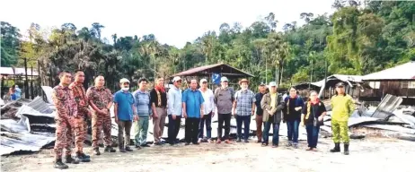  ??  ?? Roland Engan
Anyi (fifth right) and his team seen in front of what is left of the longhouse, which was burned down recently.