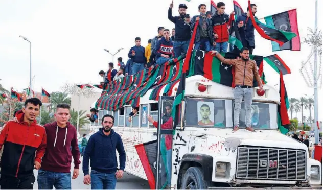  ?? Agence France-presse ?? ↑
Libyans wave national flags as they gather in Tripoli on Thursday to mark the 10th anniversar­y of the 2011 revolution.