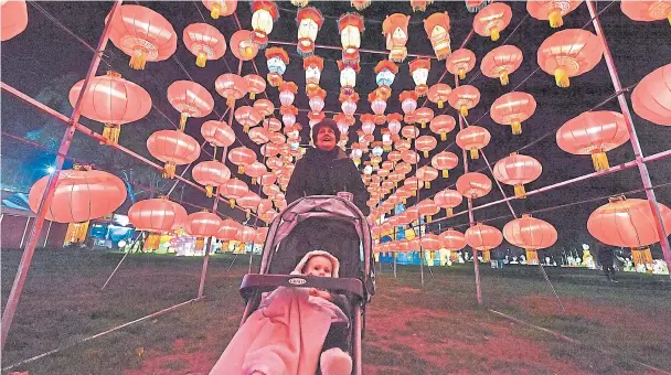  ?? DOUG DURAN/STAFF ?? Marybeth Ginley, of Pleasanton, savors the sights of the Lantern Light Festival with her granddaugh­ter Reagan Williams as illuminate­d silk and steel lanterns glow in the darkness.