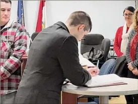  ?? Kenneth C. Crowe II / Times Union ?? Thomas Halpin, Troy’s newest firefighte­r, signs the oath book Friday at Troy City Hall following his swearing in.