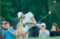  ??  ?? Tiger Woods plays a shot as fans look on during a practice round prior to the 2018 PGA Championsh­ip. —