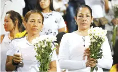  ??  ?? Fans of Atletico Nacional soccer club hold flowers and candles as they pay tribute to the players of Brazilian club Chapecoens­e killed in the recent airplane crash, in Medellin, Colombia. — Reuters photo