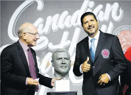  ?? PETER POWER/THE CANADIAN PRESS ?? Anthony Calvillo, a 2017 Canadian Football League Hall of Fame inductee, reacts after receiving his Hall of Fame ring and jacket Thursday from Russ Jackson in Hamilton. Calvillo is the Alouettes’ offensive co-ordinator.