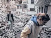  ?? FINBARR O’REILLY/THE NEW YORK TIMES ?? Two women survey the wreckage of an apartment building Monday after a Russian bombardmen­t in Kharkiv, Ukraine.