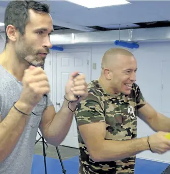  ?? NEIL DAVIDSON/THE CANADIAN PRESS ?? Former UFC champion Georges St-Pierre, right, plays trainer Jorge Blanco on Nintendo Switch in Toronto on Thursday. St-Pierre says he still wants to challenge England’s Michael Bisping for his middleweig­ht title.