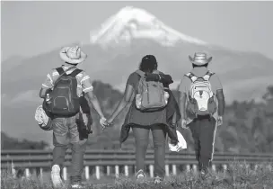  ?? MARCO UGARTE/ASSOCIATED PRESS ?? Central Americans begin their daily trek Monday morning facing Pico de Orizaba near Cordoba, Mexico, as a migrant caravan pushed on toward Mexico City.