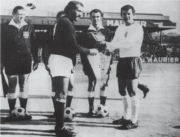  ??  ?? Maltese skipper Joe Cini and England’s Alan Mullery exchange pennants before the game in Ta’Qali in February 1971