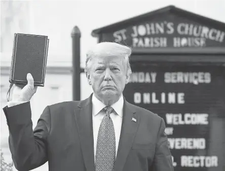  ?? PATRICK SEMANSKY/ AP ?? President Donald Trump holds up a Bible on June 1 in a photo op outside St. John’s Church across Lafayette Square from the White House, the day after the historic church was damaged by fire during protests.