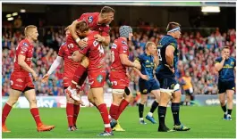  ??  ?? BLOWN AWAY: Rhys Patchell is held up (main) by Simon Zebo as the Scarlets pore forward; Gareth Davies (left) celebrates scoring the Welsh side’s third try at the Aviva Stadium yesterday