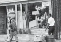  ?? THE ASSOCIATED PRESS FILE ?? A National Guard officer passes the smashed window of a blackowned flower shop in riot-torn Newark, N.J.