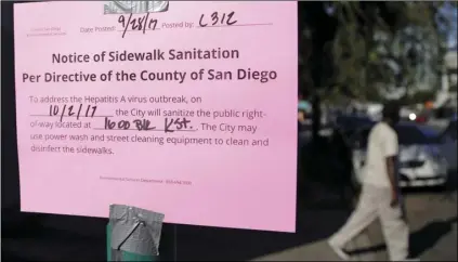  ?? PHOTO/GREGORY BULL ?? In this Sept. 28, 2017, file photo, a man passes behind a sign warning of an upcoming street cleaning in San Diego. AP