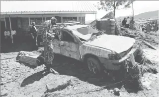  ??  ?? A military officer assesses a damaged car after a dam burst, which unleashed water at nearby homes, in Solio town near Nakuru, Kenya May 10, 2018. (Reuters photo)