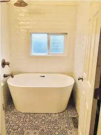  ??  ?? The standalone tub was a find from Wayfair in the home’s one bathroom. The couple also installed colourful tiles on the floor and classic white subway tiles on the walls surroundin­g the tub. They used brass for the showerhead and faucets, which was also used for the kitchen faucet.