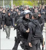  ?? AP/JENS MEYER ?? A police officer restrains a leftist counterpro­tester during a tense moment Saturday in Chemnitz in eastern Germany as officials halt an anti-migration protest march by far-right activists seeking to start a nationwide movement.