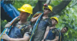  ?? (Athit Perawongme­tha/Reuters) ?? MILITARY PERSONNEL carry surface supply diving cables out from Tham Luang cave in Chiang Rai, Thailand, in July.