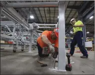  ?? (Arkansas Democrat-Gazette/Staton Breidentha­l) ?? Structurla­m employees Shane Cooper (left) and Tom Porter work at the company’s Conway facility installing production equipment.