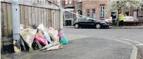  ??  ?? > Police and flowers at the scene in Chorlton yesterday