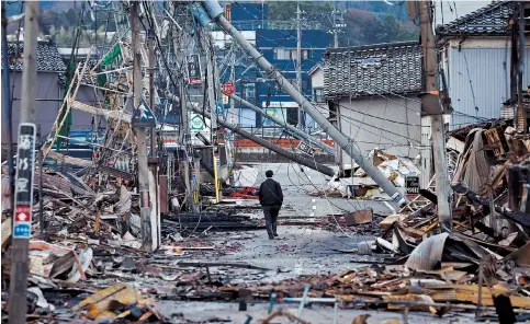  ?? ?? A man makes his way along Asaichi-dori street, which burned down in a fire after an earthquake, in Wajima, Japan, yesterday. — Reuters