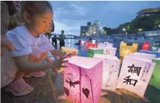  ?? — Reuters ?? A girl releases paper lanterns on the Motoyasu River facing the gutted Atomic Bomb Dome in remembranc­e of atomic bomb victims on the 73rd anniversar­y of the bombing of Hiroshima.