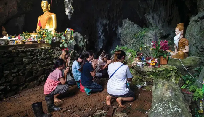 ??  ?? Family members of the 12 boys and their football coach trapped by floods in the Tham Luang cave pray at a nearby shrine as operations continue to rescue them. Photo: AFP/Getty Images