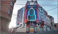  ?? JUAN KARITA / ASSOCIATED PRESS ?? People walk next to a mini mansion inspired by the Transforme­rs franchise in La Paz, Bolivia. The designer has created five such buildings in the country.