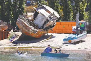  ?? Amy Osborne / Special to The Chronicle ?? Robbie Powelson, president of the Marin Homeless Union, swims with a Camp Cormorant flag to a boat at Marinship Park in Sausalito, where seized vessels from the anchorout community wait to be destroyed.