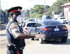  ??  ?? A police officer directs traffic at the intersecti­on of Constant Spring and Mannings Hill roads on Monday morning.