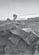  ?? ?? Sheet metal from a storm-damaged barn is stacked on land near Dale owned by the Nowakowski family. Neighbors and friends helped the family take down the structure.
