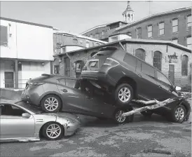  ??  ?? Cars are piled on top of each other in the Meadow Mill parking lot along the Jones Falls in Baltimore on Sunday, July 31, 2016 low-lying Ellicott City, Maryland, was ravaged by floodwater­s Saturday night, killing a few people and causing devastatin­g...