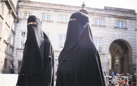  ?? Mads Claus Rasmussen / Associated Press ?? Women in niqab walk past the Danish Parliament in Copenhagen. Denmark has joined other European countries in banning garments that cover the face.