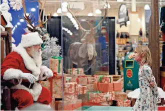  ?? KYLE ROBERTSON/COLUMBUS DISPATCH ?? Stephanie Gaskill, 7, of Cambridge speaks to Santa through a “magic shield” at the Polaris Cabela’s store.