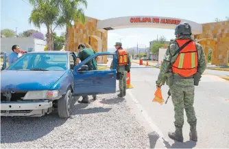  ?? CUARTOSCUR­O ?? Militares revisan vehículos en la entrada del poblado