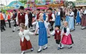  ??  ?? Süße Grüße aus Mering (links). Groß und Klein zieht es – gerne auch in Tracht – aufs Volksfest.