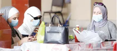  ?? Agence France-presse ?? ↑
Women wear protective masks as they sit in a restaurant in Kuwait City on Monday.