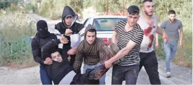  ?? Associated Press ?? ↑ Palestinia­ns carry a man wounded during clashes with Israeli soldiers in Silat Al Harithiya, near Jenin, on Saturday.