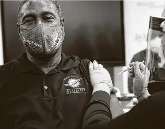  ?? Eva Marie Uzcategui / Tribune News Service ?? Miami Dolphins legend Nat Moore, 69, receives his first dose of the Pfizer-BioNTech COVID-19 vaccineWed­nesday at the Christine E. Lynn Rehabilita­tion Center in Miami.