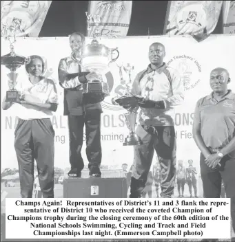  ?? ?? Champs Again! Representa­tives of District’s 11 and 3 flank the representa­tive of District 10 who received the coveted Champion of Champions trophy during the closing ceremony of the 60th edition of the National Schools Swimming, Cycling and Track and Field Championsh­ips last night. (Emmerson Campbell photo)